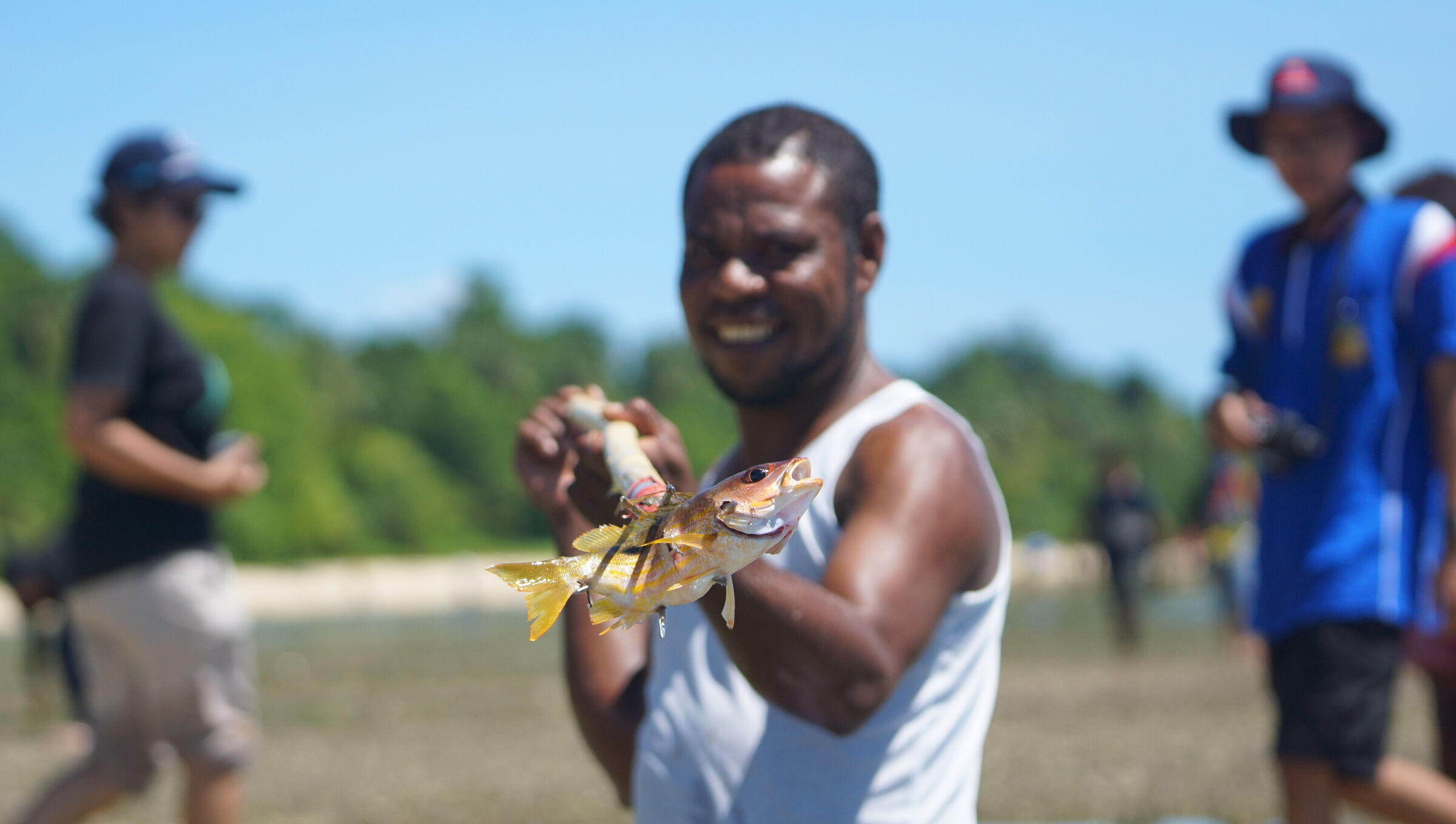 A man on the beach holding up two small fish at Snap Mor, the traditional reef-walking harvest