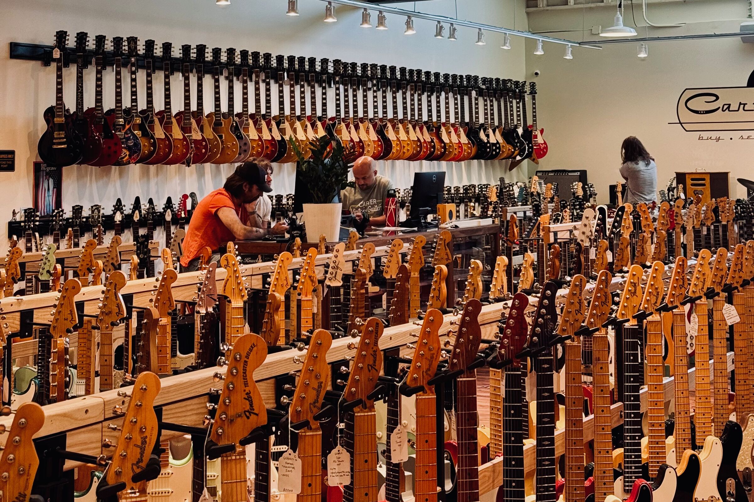 The interior of Carter Vintage Guitars, racks of electric guitars stretching across the floor with more hung along the back wall