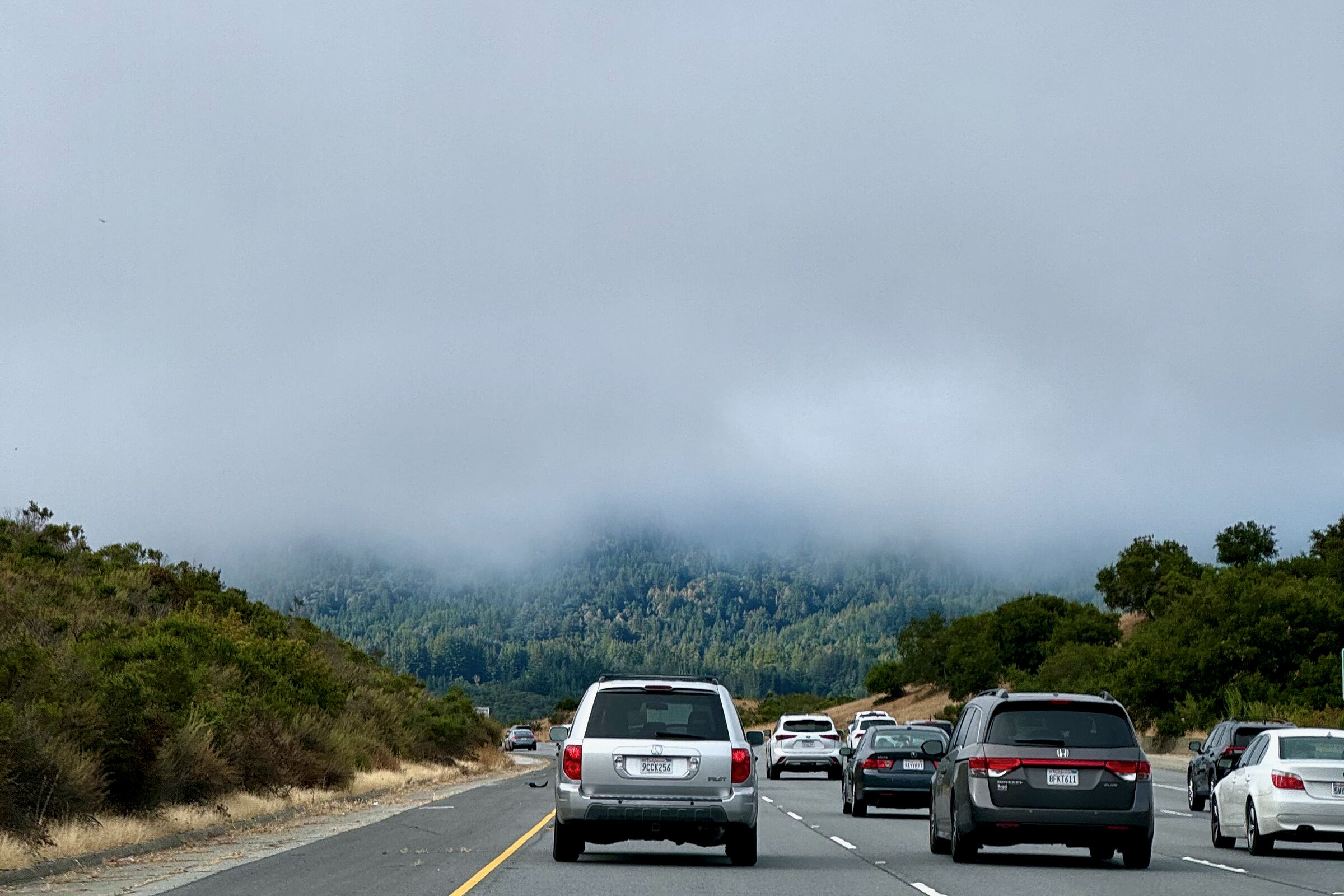 Northbound highway with cars and fog rolling over the hills ahead